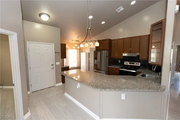 a kitchen with stainless steel appliances granite countertop a refrigerator a oven a sink with wooden cabinets and outdoor