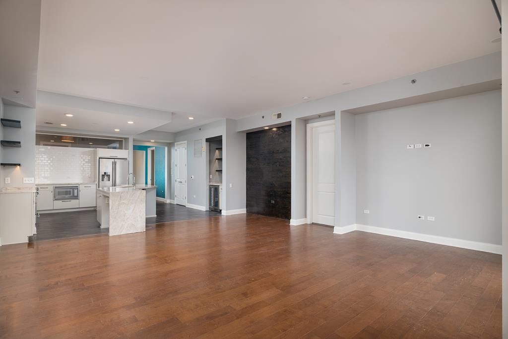 717 Riverside Drive, Unit 1105 Memphis, TN 38103 - Photo 9 of 29 Unfurnished living room with dark wood-type flooring, recessed lighting, and wine cooler