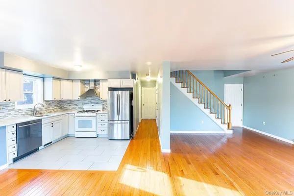 a view of a kitchen with kitchen island a sink wooden floor and a living room