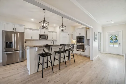 a view of kitchen with stainless steel appliances granite countertop a stove a sink a table and chairs