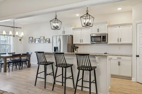 a kitchen with stainless steel appliances granite countertop a sink dishwasher a stove top oven a refrigerator with wooden cabinets and floor