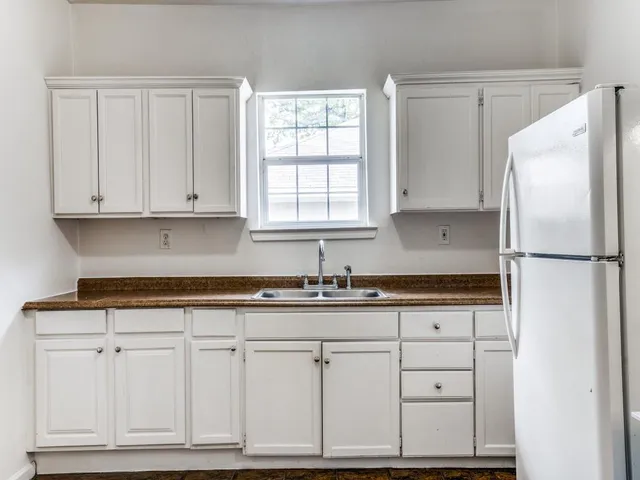 a kitchen with granite countertop white cabinets and a refrigerator