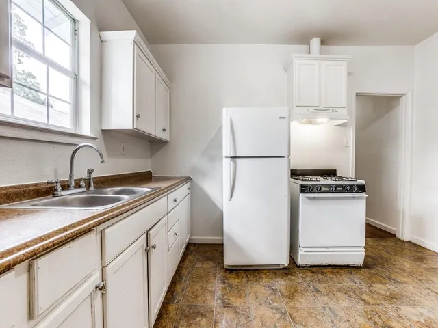 a kitchen with a refrigerator sink and white cabinets