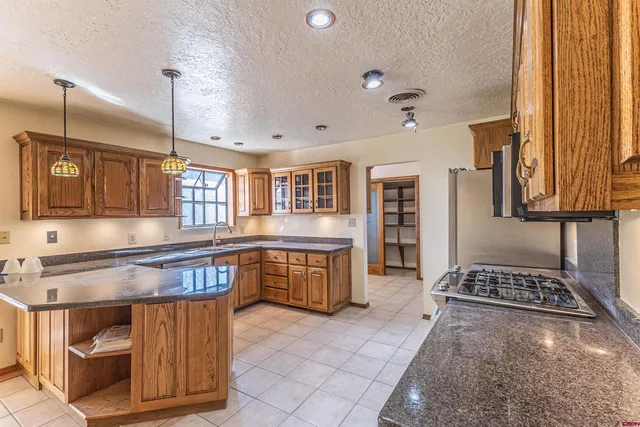 a kitchen with stainless steel appliances granite countertop a stove top oven a sink a dining table and chairs with wooden floor