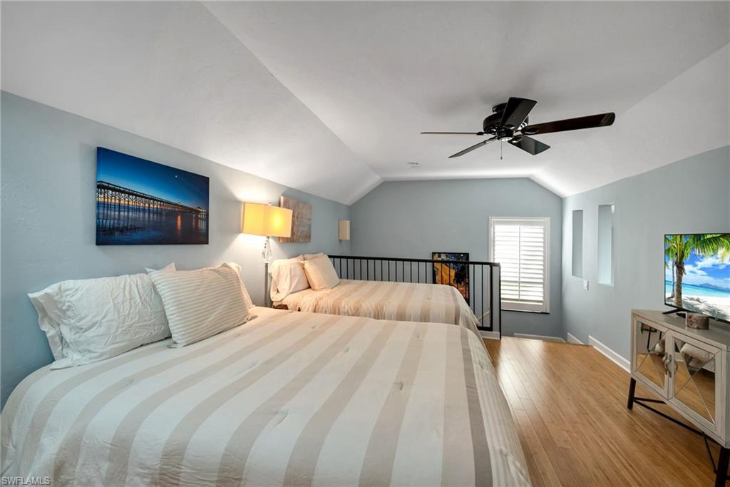 1269 Solana Road, Unit E3 Naples, FL 34103 - Photo 12 of 23 a bedroom with a bed a dresser and a chandelier