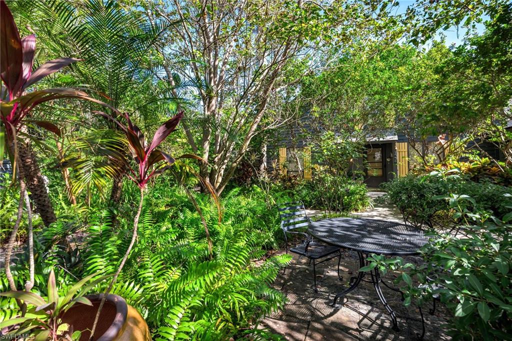 1269 Solana Road, Unit E3 Naples, FL 34103 - Photo 18 of 23 a backyard of a house with table and chairs under an umbrella
