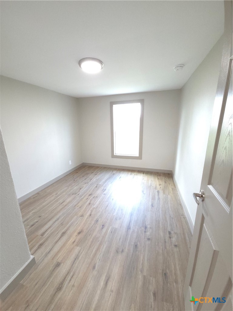 2605 Plainview Street Victoria, TX 77901 - Photo 6 of 16 an empty room with wooden floor and windows