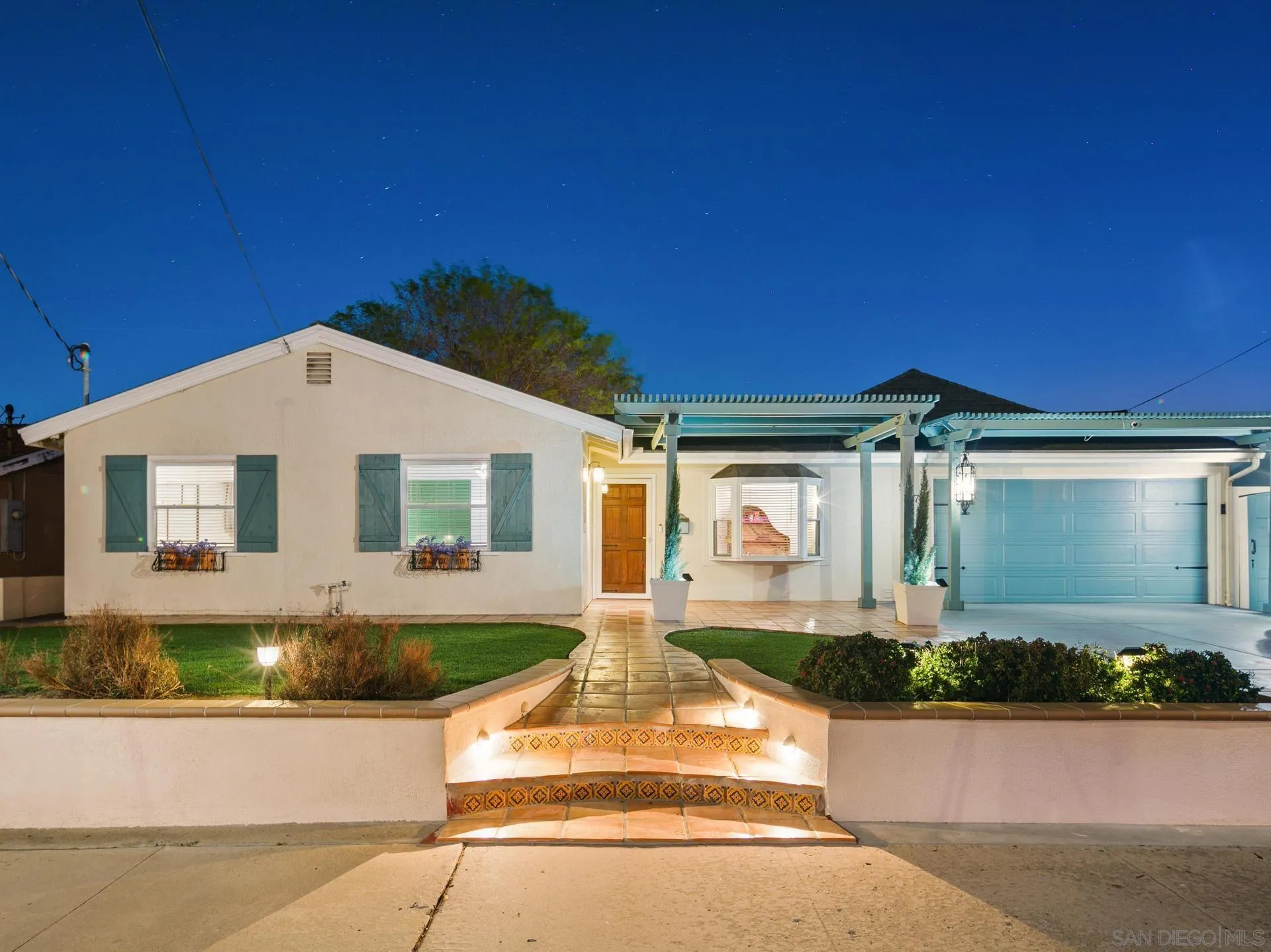 a front view of a house with a yard and potted plants
