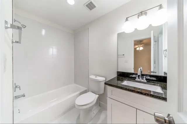 a bathroom with a granite countertop sink a toilet a mirror and bathtub