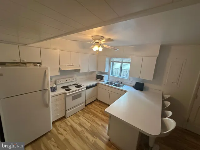 a kitchen with a sink a stove cabinets and wooden floor