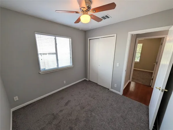 an empty room with windows and fan