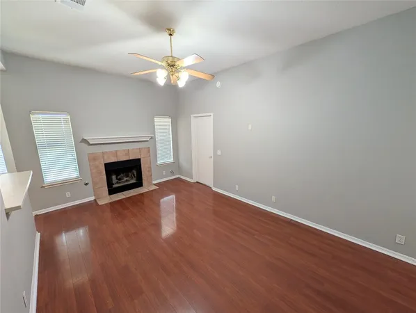 a view of an empty room with wooden floor and a fireplace