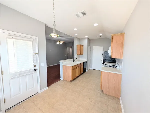a large kitchen with stainless steel appliances a large counter top a stove a chimney a sink and a refrigerator