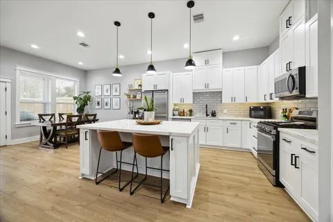 a large kitchen with cabinets and chairs