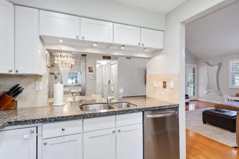 a kitchen with granite countertop a sink and white cabinets