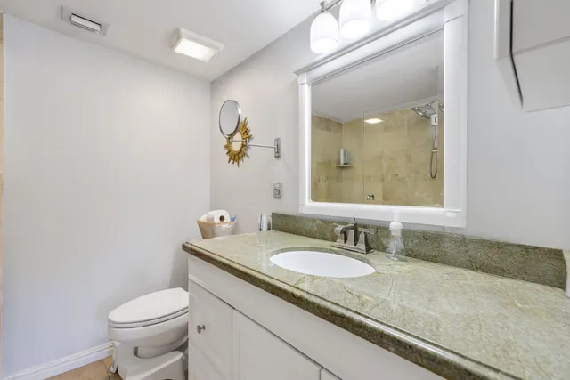 a bathroom with a granite countertop sink a toilet and a mirror