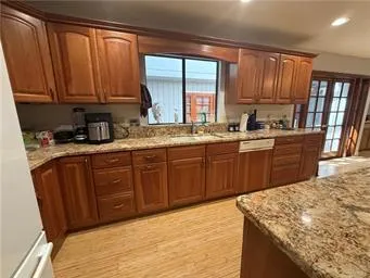 a kitchen with stainless steel appliances granite countertop wooden cabinets a sink and dishwasher with wooden floor