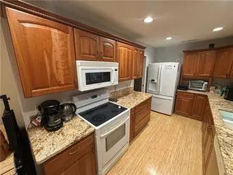 a kitchen with granite countertop wooden cabinets and a stove top oven