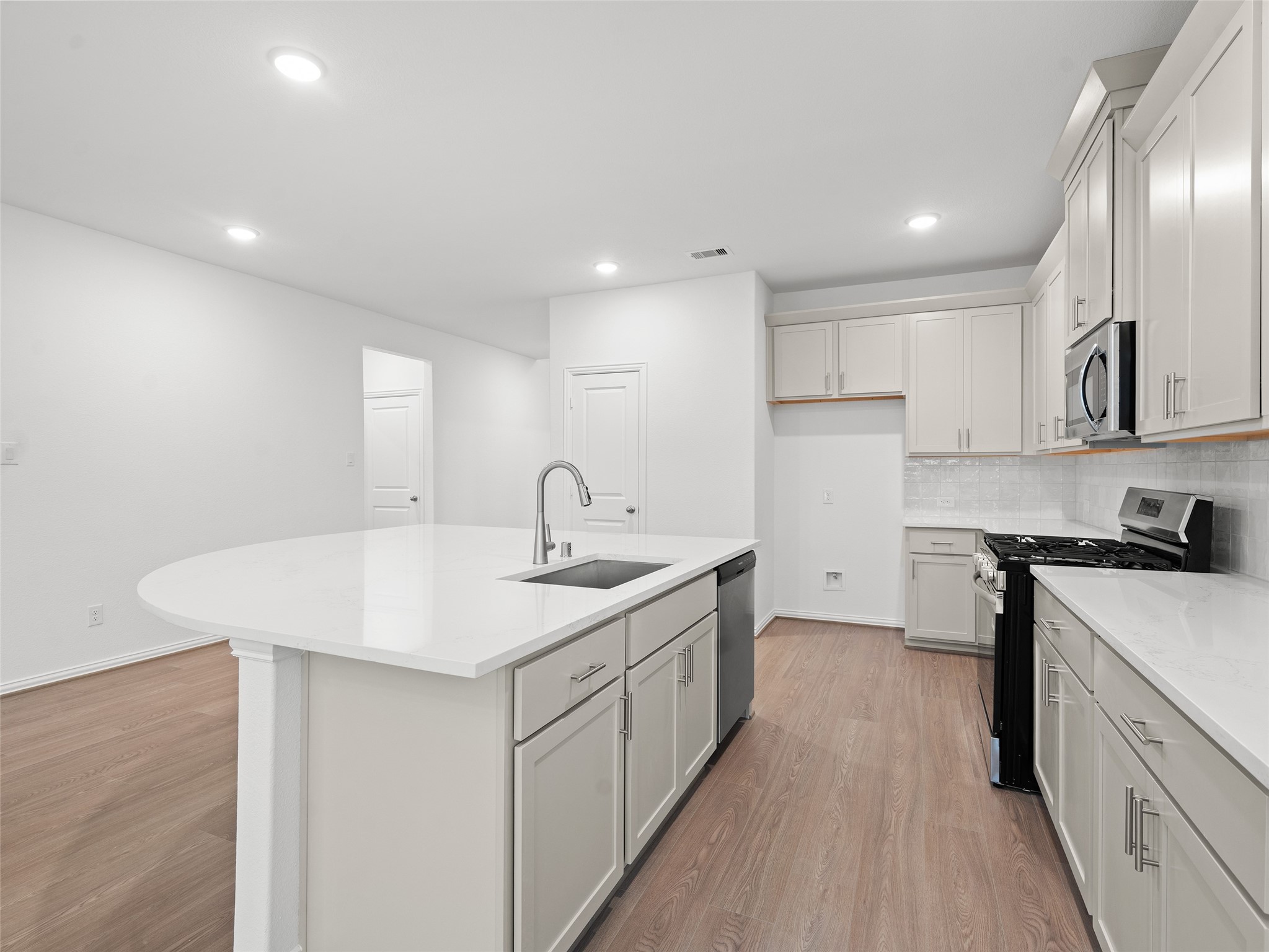 410 Strm Bnd Way Rosenberg, TX 77471 - Photo 11 of 39 a kitchen with a sink a stove a refrigerator and white cabinets