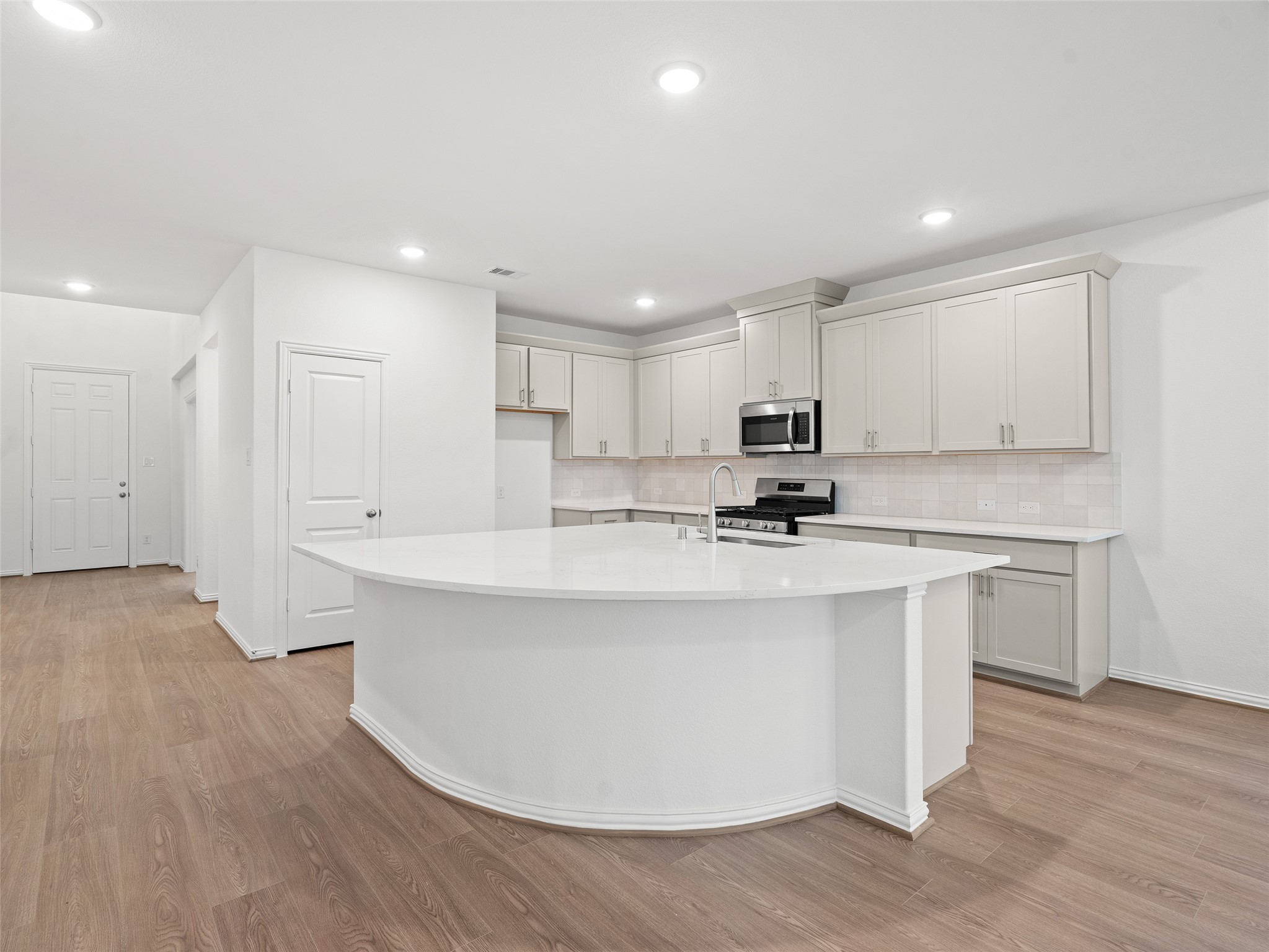 410 Strm Bnd Way Rosenberg, TX 77471 - Photo 12 of 39 a kitchen with stainless steel appliances granite countertop a stove a sink a refrigerator and white cabinets with wooden floor