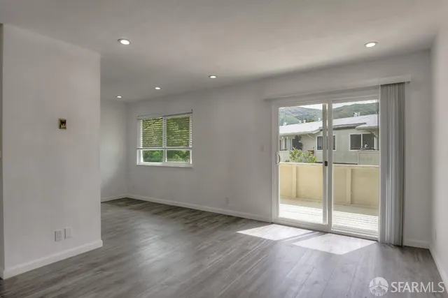 an empty room with wooden floor and windows