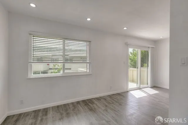 an empty room with wooden floor and windows