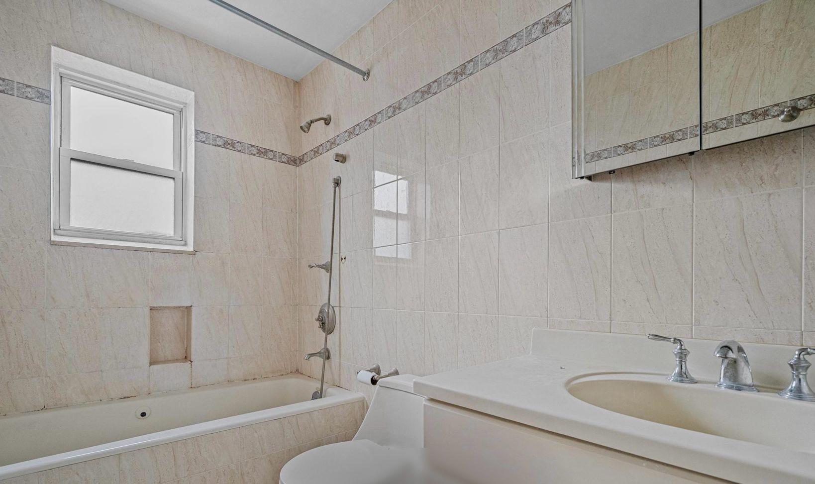 138-12 76th Avenue Queens, NY 11367 - Photo 8 of 12 Bathroom featuring tile walls, tiled shower / bath combo, toilet, and vanity