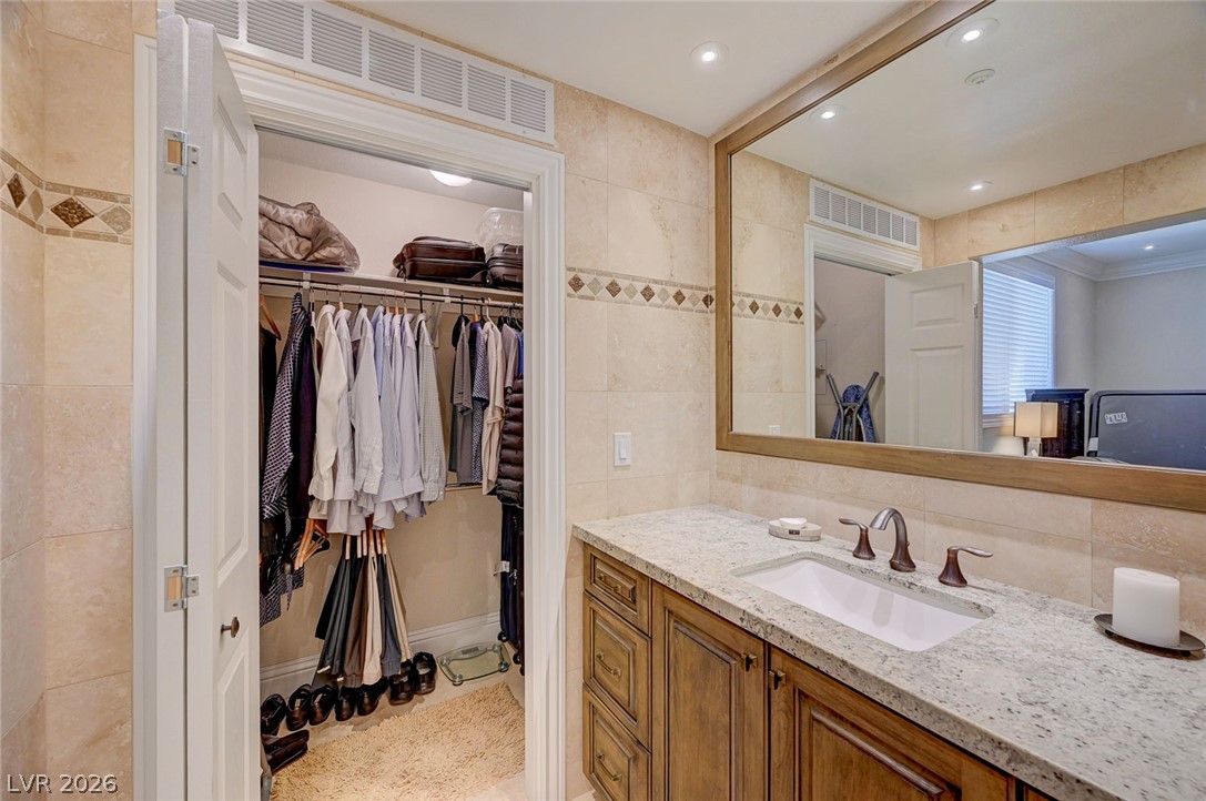 230 East Flamingo Road, Unit 106 Las Vegas, NV 89169 - Photo 16 of 66 A well-organized walk-in closet adjoins a vanity with a large mirror and stone counters.
