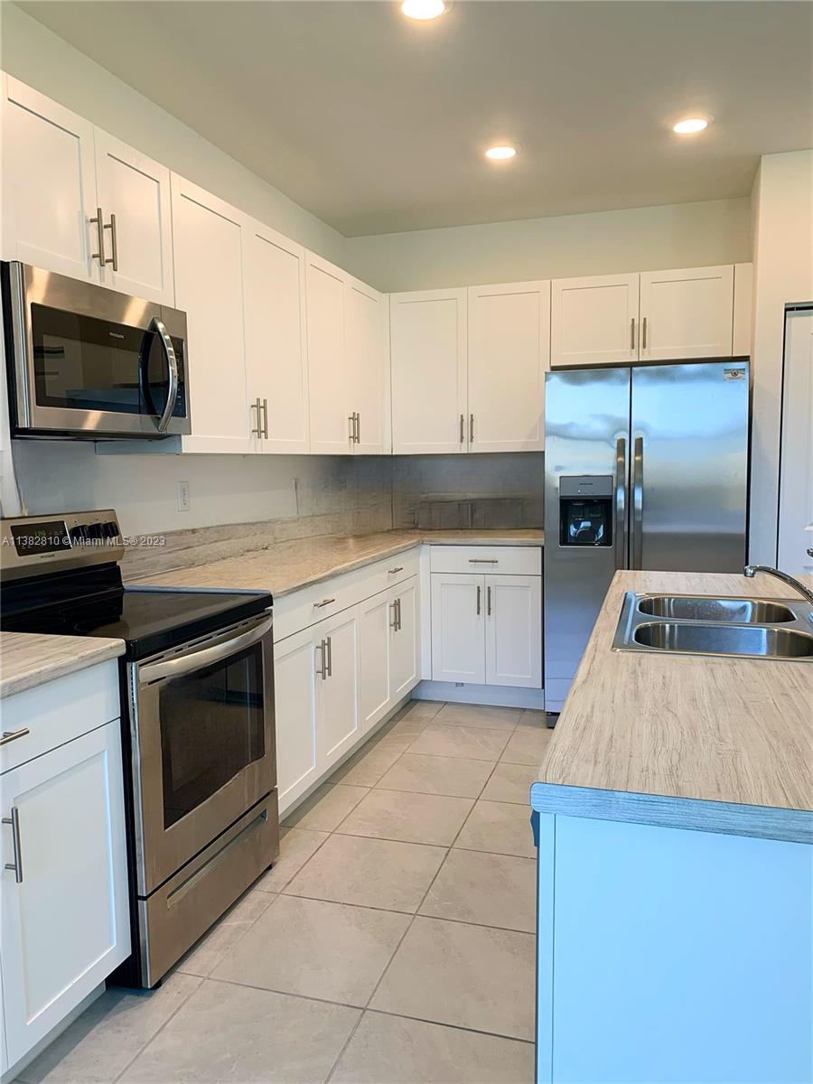11909 Southwest 244th Street, Unit 11909 Homestead, FL 33032 - Photo 9 of 45 a kitchen with a sink a stove and oven