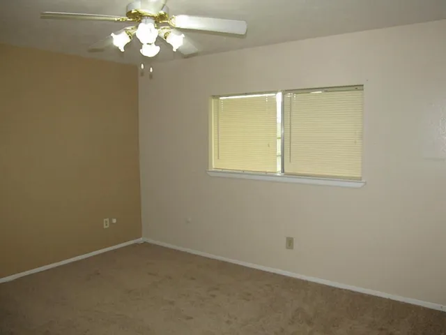 an empty room with a chandelier fan and a table
