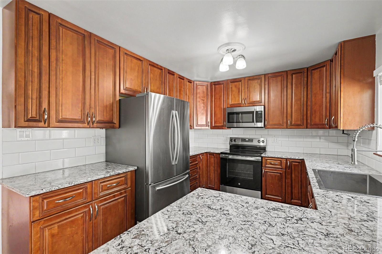3217 South Stuart Street Denver, CO 80236 - Photo 8 of 29 a kitchen with stainless steel appliances granite countertop a refrigerator stove top oven and sink