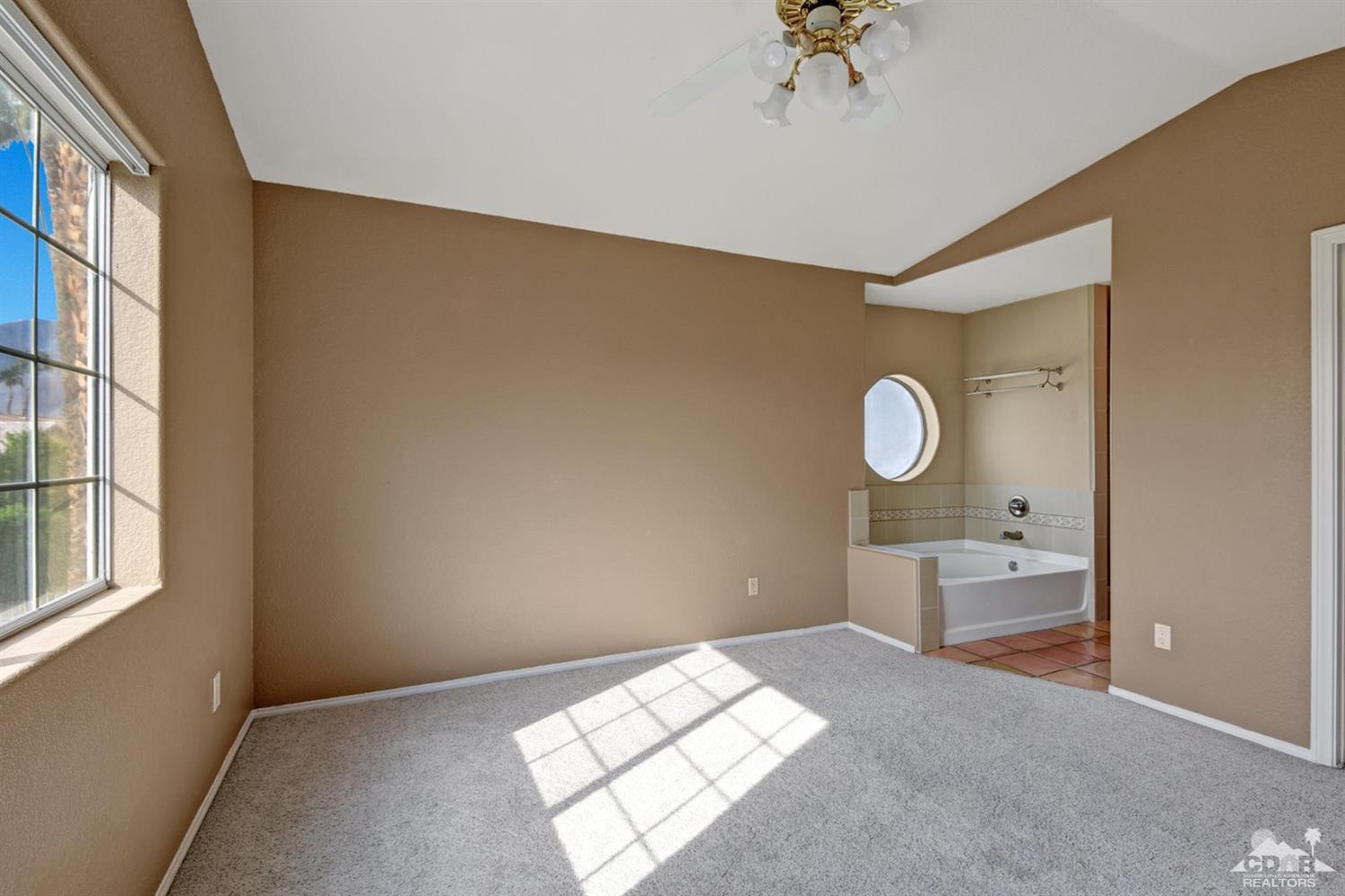68889 Risueno Road Cathedral City, CA 92234 - Photo 16 of 29 a bedroom with a bed and a chandelier