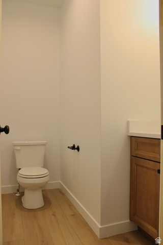 2613 Scarlet Road, Unit 258 Eagle Mountain, UT 84005 - Photo 13 of 32 Powder room featuring wood-finish flooring, a white toilet, and a vanity with a light-colored countertop and wood-finish cabinetry