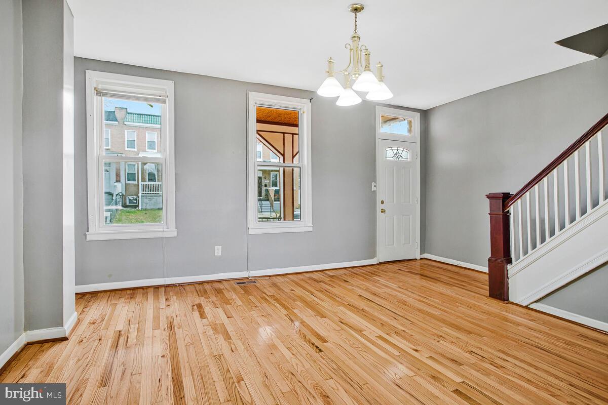 5204 Ivanhoe Avenue Baltimore, MD 21212 - Photo 8 of 38 an empty room with wooden floor chandelier and windows