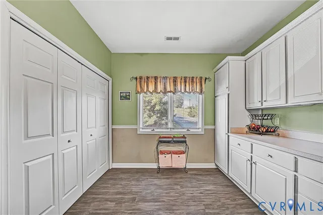 a kitchen that has a lot of white cabinets and stainless steel appliances