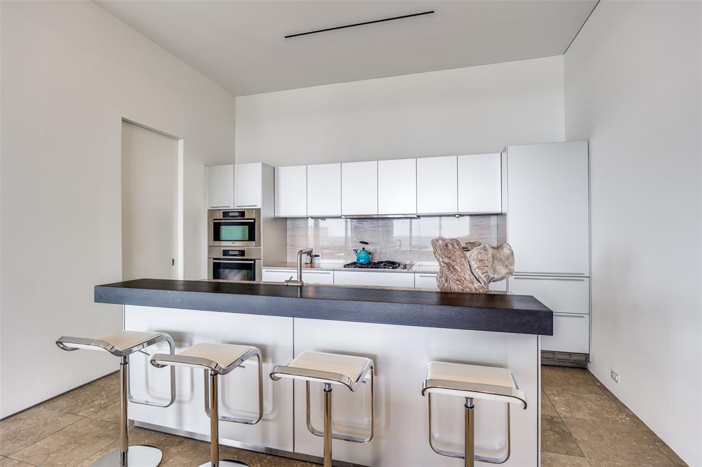 1717 Arts Plaza, Unit 1808 Dallas, TX 75201 - Photo 7 of 30 Kitchen with appliances with stainless steel finishes, dark countertops, a breakfast bar area, decorative backsplash, and white cabinetry