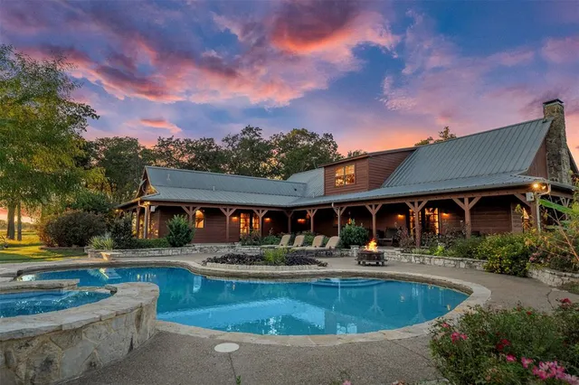 a view of a house with swimming pool and a chairs and table in a patio