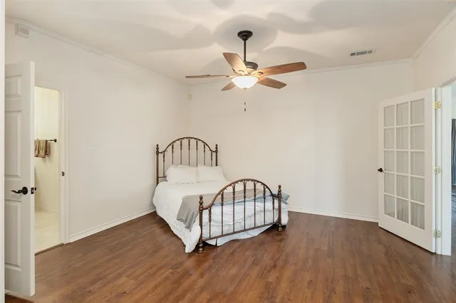 a view of a bedroom with wooden floor & a ceiling fan