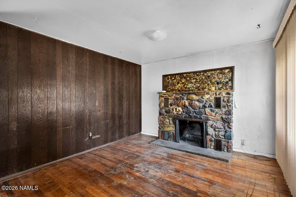 a view of an empty room with wooden floor fireplace and a window