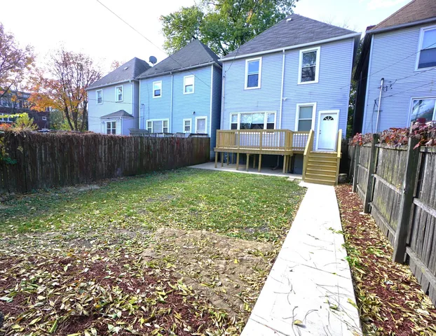 a view of a house with backyard and wooden fence