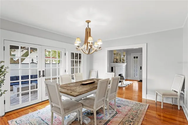 a dining room with wooden floor a chandelier a wooden table and chairs