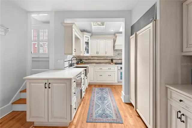 a kitchen with granite countertop a sink cabinets stainless steel appliances and a window
