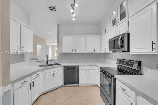 a kitchen with stainless steel appliances granite countertop a refrigerator a stove and a sink