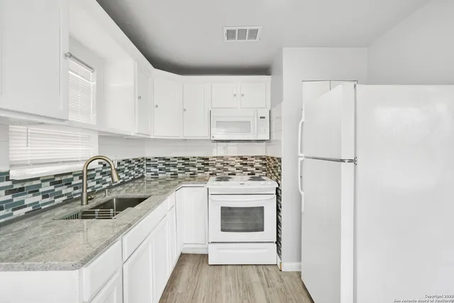 a kitchen with granite countertop a sink stove and refrigerator
