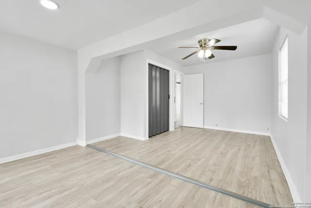 a view of empty room with wooden floor and ceiling fan
