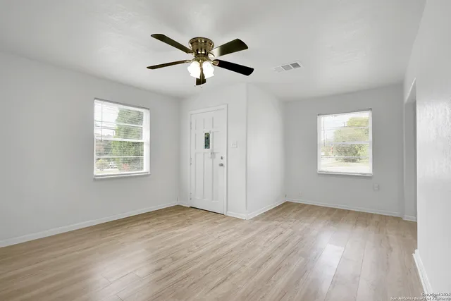 a view of an empty room with wooden floor and a window