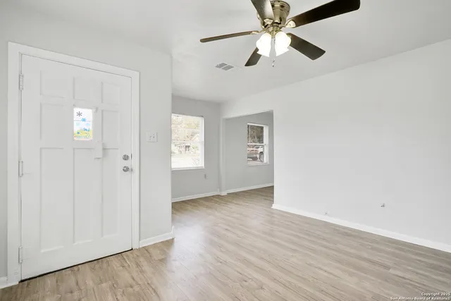 an empty room with wooden floor closet and windows fan