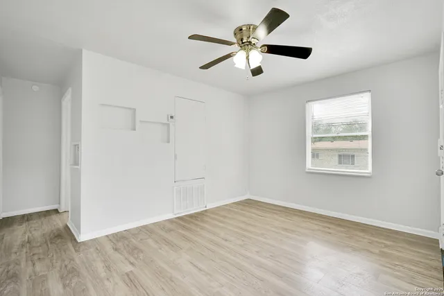 an empty room with wooden floor and windows