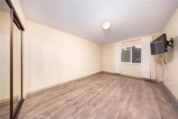 a view of empty room with wooden floor and fan