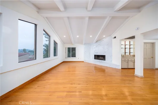 a view of an empty room with wooden floor and a fireplace